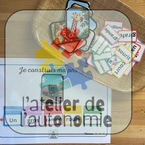 Pode incluir: Materiais educativos para crianças, incluindo cartões com imagens de animais, como uma girafa, e cartões de palavras. O conjunto inclui um tabuleiro de jogo tipo puzzle com os textos "Je construis ma phrase" e "l'atelier de l'autonomie".