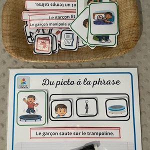 Peut inclure: Un ensemble pédagogique avec des cartes flash et un tableau blanc. Les cartes flash sont dans un panier tressé et présentent des illustrations et du texte. Le tableau blanc porte le titre "Du picto à la phrase".