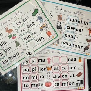 Può includere: Tre fogli di attività educative plastificati intitolati La chasse aux syllabes che mostrano griglie con parole francesi divise in sillabe, accompagnate da illustrazioni colorate di oggetti come un robot, una moto, una farfalla e un pomodoro.