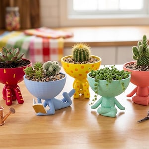 May include: A collection of whimsical, colorful planters shaped like human figures, each holding a different succulent or cactus. The planters are red, blue, yellow, green, and coral, with unique designs and poses. A small copper watering can and scissors are also present.
