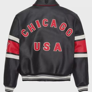 May include: Black leather jacket with red and white accents. The back features the word "CHICAGO" arched across the top and "USA" below, in red lettering with white outlines. White stripes and red panels adorn the sleeves.