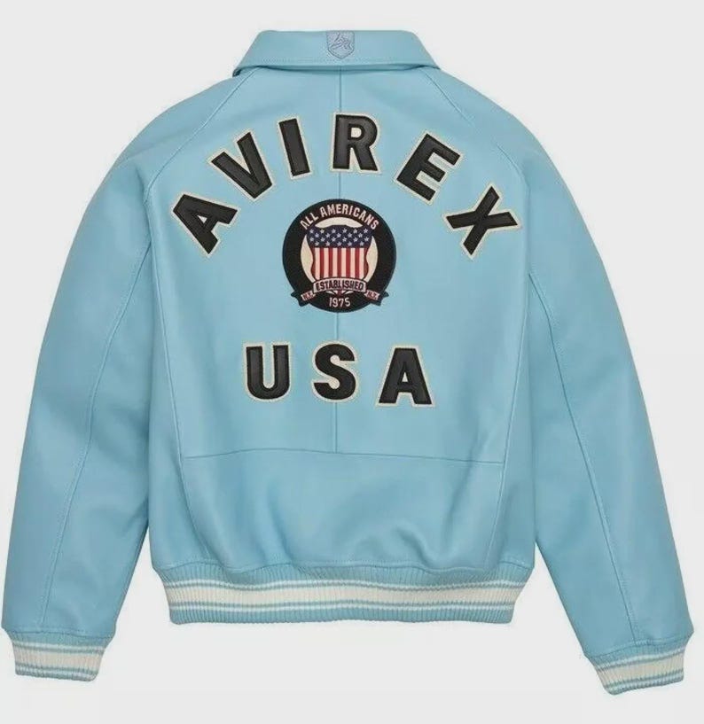 May include: Light blue leather jacket with the word "AVIREX" across the back in black letters. Below the word "AVIREX" is a circular patch with the words "ALL AMERICANS" and "ESTABLISHED 1975". Below the patch is the word "USA".