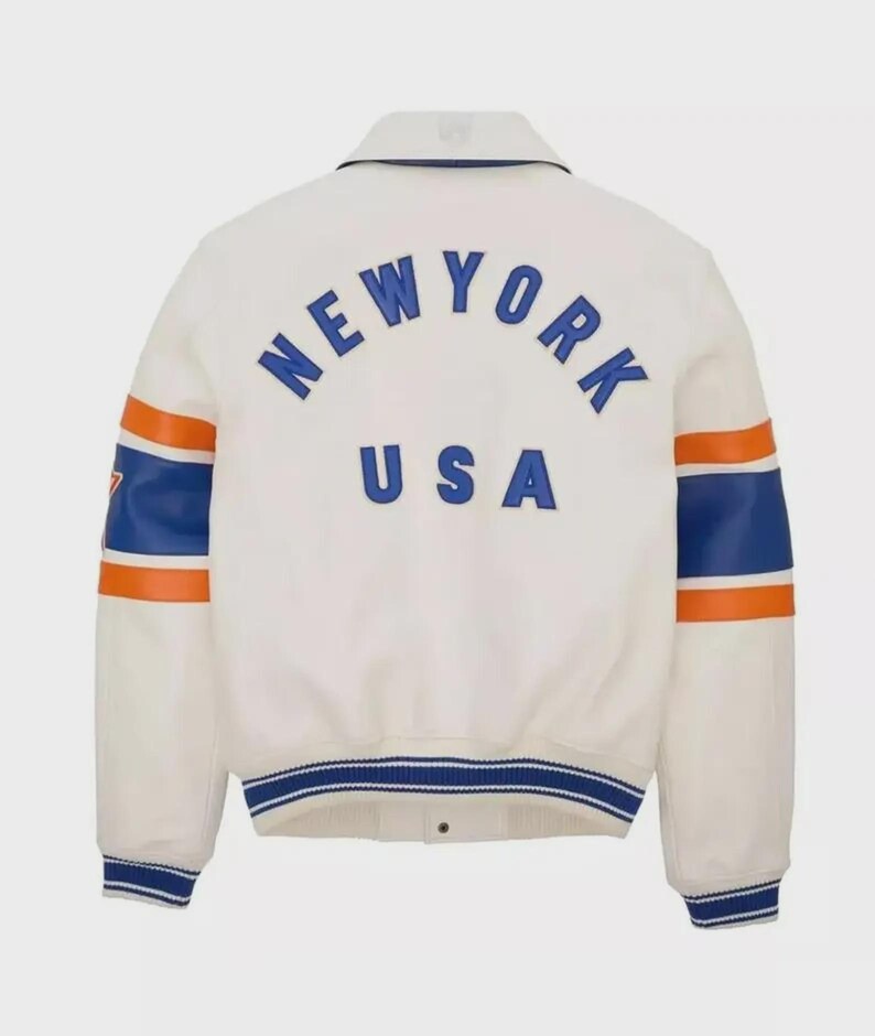 May include: Cream-colored jacket with the word "NEW YORK" arched across the back in blue lettering, with "USA" underneath. The sleeves have blue and orange stripes. The jacket has a collar and a blue and white striped trim.