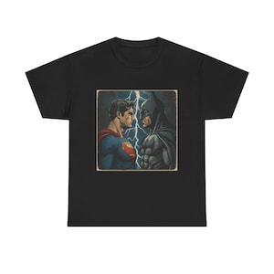 May include: Black t-shirt featuring a vintage-style graphic of Superman and Batman facing each other, with lightning in the background. The image is framed in a square with a distressed border. The shirt is made of a soft, comfortable material.