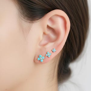 Orecchini a lobo con fiore turchese, margherita dorata e cristallo centrale, gioielli botanici in stile boho.