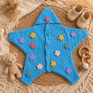 May include: A bright blue crocheted star-shaped hooded garment with a front button closure. The piece is decorated with small, multi-coloured crocheted flower appliques in shades of pink, yellow, purple, and grey, featuring ribbed cuffs.