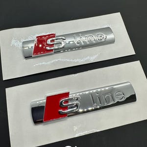 May include: Two chrome S line emblems with a red accent. The emblems are rectangular with the text "S line" and a stylized "S" logo. The word "Chrome" is printed at the bottom.