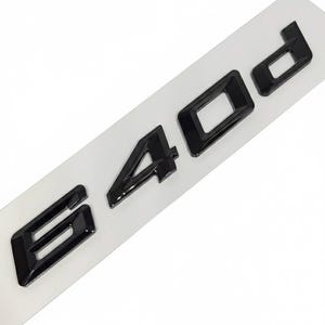 Pode incluir: Emblema preto brilhante "E 40 d" sobre fundo branco. As letras e números tridimensionais têm uma superfície refletora. Provavelmente para uso automotivo.