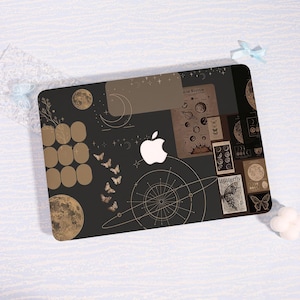 May include: A black laptop skin featuring a white Apple logo in the center, surrounded by celestial illustrations including moons, a solar system diagram, stars, butterflies, and geometric lines. The design includes text labels like Solar System and Butterfly.