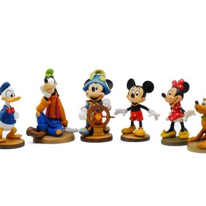 May include: A collection of Disney character figurines, including Donald Duck, Goofy, Mickey Mouse, Minnie Mouse, and Pluto. Each figurine is brightly colored and stands on a small, round base. The characters are in various poses.