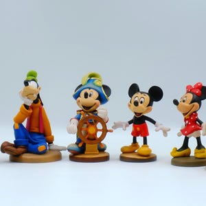 May include: A collection of Disney character figurines, including Donald Duck, Goofy, Mickey Mouse, Minnie Mouse, and Pluto. The figures are brightly colored and stand on individual bases, showcasing classic cartoon designs.