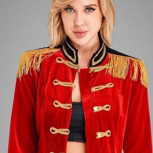 May include: A red velvet jacket featuring a high collar, gold braided cord closures, and gold metallic buttons. The shoulders are adorned with gold fringe epaulets, and the cuffs and collar are trimmed with black fabric accents.