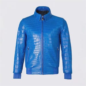May include: A vibrant blue leather jacket with a crocodile skin texture. The jacket features a zip-up front, a stand-up collar, and ribbed cuffs and hem. The jacket has two side pockets and a small pocket on the left sleeve.