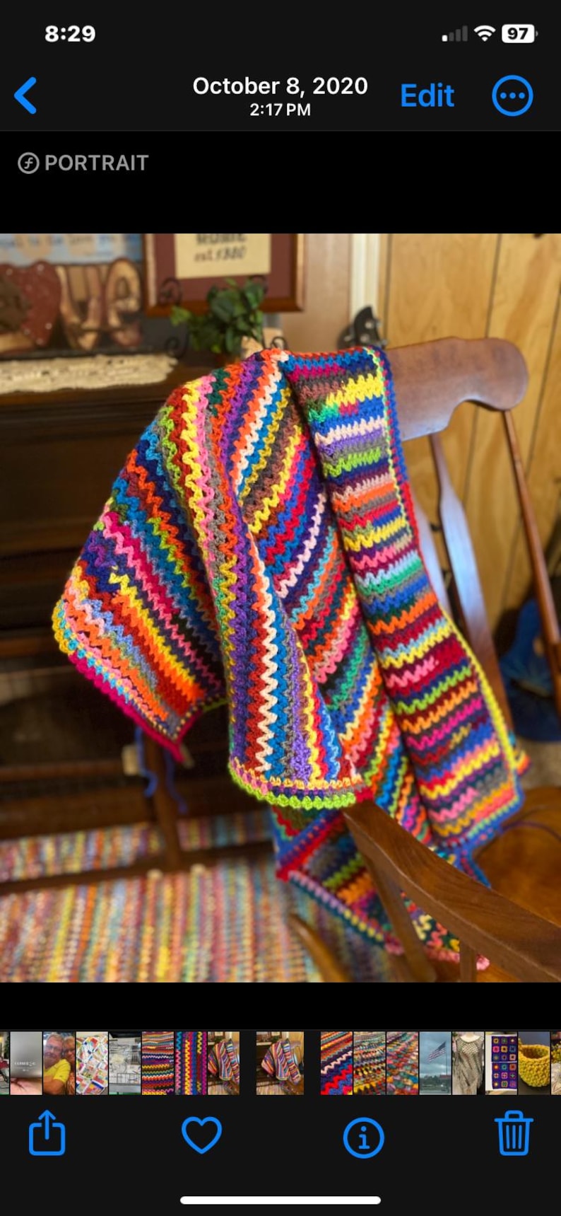 May include: A colorful crocheted blanket draped over a wooden rocking chair. The blanket is made with a variety of bright colors, including red, orange, yellow, green, blue, purple, and pink.