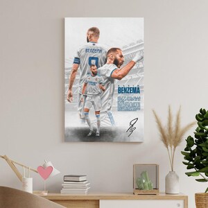 Może przedstawiać: Wydruk na pł&oacute;tnie przedstawiający kilka zdjęć Karima Benzemy w białym stroju piłkarskim. Nazwisko "Benzema" jest wyświetlane niebieskim tekstem, wraz z jego podpisem. Tło ma wz&oacute;r stadionu.