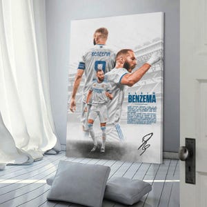 Może przedstawiać: Oprawiony plakat przedstawiający Karima Benzemę w białej koszulce piłkarskiej z numerem 9. Plakat zawiera wiele zdjęć Benzemy, imię "BENZEMA" w kolorze niebieskim i podpis. Tło przedstawia stadion.