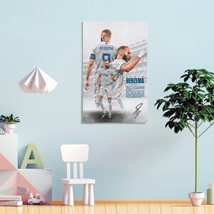 Może przedstawiać: Wydruk na pł&oacute;tnie przedstawiający piłkarza w białej koszulce z nazwiskiem "Benzema" i numerem 9. Obraz zawiera wiele p&oacute;z zawodnika, podpis i nazwę "Benzema" w niebieskiej czcionce.