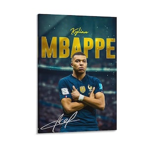 May include: A portrait of Kylian Mbappé in a blue jersey with the French national team emblem. The name "MBAPPE" is in large gold letters above the player's head, with his signature at the bottom. The background is a blurred stadium.