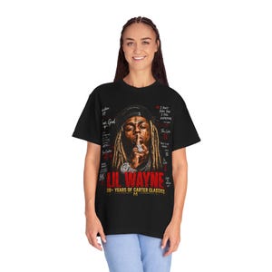 Puede incluir: Una camiseta negra de manga corta con un gr&aacute;fico de Lil Wayne con rastas, gorra y joyas. El dise&ntilde;o incluye el texto en rojo LIL WAYNE 20+ YEARS OF CARTER CLASSICS y varias citas y t&iacute;tulos de &aacute;lbumes con un estilo de escritura a mano.