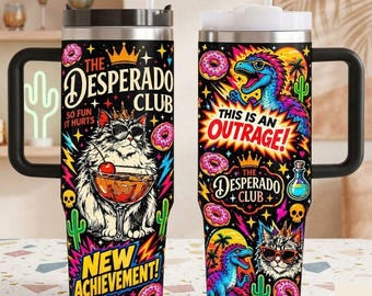 May include: Two stainless steel tumblers with black handles and lids, featuring a vibrant black background with colorful illustrations of cats wearing sunglasses, dinosaurs, donuts, cacti, and skulls, with text reading The Desperado Club.