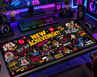 May include: A rectangular black desk mat featuring a vibrant, multi-colored graphic print with the text NEW ACHIEVEMENT! and various cartoon illustrations including a treasure chest, a dinosaur, cats, and humorous phrases like YOU WILL NOT BREAK ME.