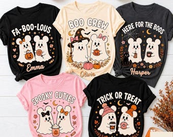 May include: Five short-sleeved t-shirts in black, cream, and pink featuring Halloween-themed graphics of cartoon ghosts with mouse ears. Each shirt displays unique text including FA-BOO-LOUS, BOO CREW, HERE FOR THE BOOS, SPOOKY CUTIES, and TRICK OR TREAT.