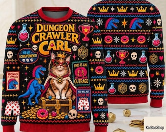 May include: A black long-sleeve sweater featuring a graphic of a cat wearing a crown and glasses, sitting on a treasure chest. The design includes a blue dinosaur, skulls, donuts, crowns, and text reading Dungeon Crawler Carl, New Achievement, This Is An Outrage, and You Will Not Break Me.