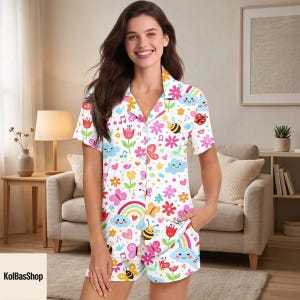 May include: White pajama set with a colorful floral, butterfly, bee, and rainbow pattern. The short-sleeved top has a button-down front and a collar. The shorts have a matching print and a pocket.