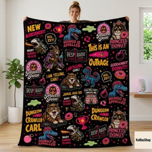 May include: A black fleece blanket featuring a repeating graphic pattern of cartoon cats, dinosaurs, and donuts. Text includes "New Achievement," "Princess Posse," "Desperado Club," "Mongo is Appalled," "Dungeon Crawler Carl," and "I am yelling, Carl!"
