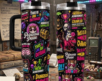 May include: A black stainless steel tumbler with a handle, featuring a vibrant, multi-colored graphic print of cats wearing crowns, dinosaurs, skulls, and trophies, along with text including "Princess Posse," "This is an outrage," and "New achievement."