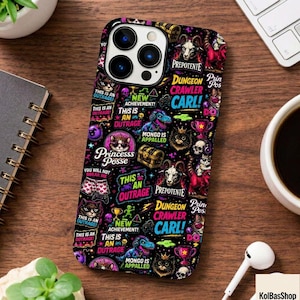 May include: A black smartphone case featuring a vibrant, multi-colored graphic pattern with various illustrations including cats, skulls, treasure chests, and trophies, alongside text such as Dungeon Crawler Carl, Prepotente, and This is an Outrage.