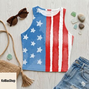 K&ouml;nnte beinhalten: Ein &auml;rmelloses Crop-Top mit einem patriotischen Design in Blau, Wei&szlig; und Rot. Die linke Seite hat einen blauen Hintergrund mit wei&szlig;en Sternen, und die rechte Seite hat rote und wei&szlig;e Streifen. Das Top wird mit Jeansshorts und Sonnenbrille kombiniert.