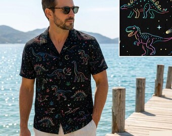May include: A black short-sleeve button-down shirt featuring a colorful neon-style dinosaur and star pattern. The shirt has a classic collar and a button-front closure, showcasing various dinosaur silhouettes in vibrant outlines against a dark background.