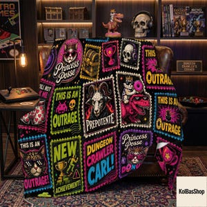 May include: A black fleece blanket featuring a vibrant, multi-colored grid of graphic patches. Designs include a cat with sunglasses, a goat with headphones, a dinosaur, a skull, trophies, and text such as Princess Posse, This Is An Outrage, and Dungeon Crawler Carl.