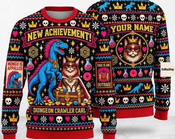 May include: A black long-sleeve sweater featuring a colorful pattern with a blue dinosaur and a cat wearing glasses and a crown. The text reads NEW ACHIEVEMENT, DUNGEON CRAWLER CARL, MONGO IS APPALLED, THIS IS AN OUTRAGE, and YOUR NAME. Includes skulls, crowns, and hearts.