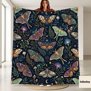 May include: A dark blue throw blanket featuring a repeating pattern of various moths, ferns, mushrooms, and celestial symbols like stars and crescent moons. The moths are depicted in shades of purple, gold, green, and brown with intricate wing details.