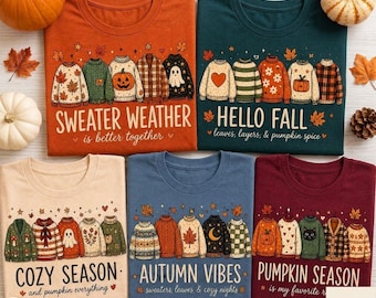 May include: Five t-shirts in orange, dark green, beige, blue, and maroon, each featuring a graphic of five sweaters and autumn-themed text. The designs include illustrations of pumpkins, leaves, ghosts, and cats, with phrases like Sweater Weather, Hello Fall, Cozy Season, Autumn Vibes, and Pumpkin Season.