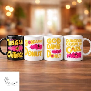 May include: Four ceramic mugs with humorous phrases. One black mug reads "THIS IS AN OUTRAGE" with yellow and pink accents. The other three white mugs say "GODDAMNIT DONUT!", "GOD DAMN DONUT", and "DUNGEON CRAWLER CARL" in yellow and pink.