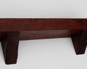 May include: A dark brown wooden shelf with two triangular supports. The shelf is made of reclaimed wood and has a rustic look.