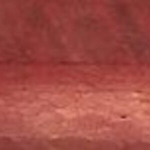 May include: A close-up of a smooth, reddish-brown wooden surface. The wood has a natural grain pattern and a slightly glossy finish.