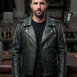 May include: A dark green motorcycle jacket with a textured snakeskin pattern, featuring a wide notched collar, silver-tone metal zippers, snap button details, and long sleeves with zippered cuffs. The jacket is worn over a plain black t-shirt.