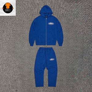 Puede incluir: Un conjunto a juego en azul real que consta de una sudadera con capucha y cremallera de manga larga y pantalones de ch&aacute;ndal. La sudadera cuenta con capucha, una cremallera frontal completa y un gr&aacute;fico ovalado de color blanco en el pecho.
