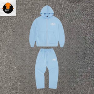 Puede incluir: Un conjunto a juego de color azul claro que consta de una sudadera con capucha y cremallera y pantalones de ch&aacute;ndal. La sudadera tiene una cremallera frontal completa, capucha y un peque&ntilde;o logotipo ovalado blanco en el pecho. El pantal&oacute;n tiene un logo.