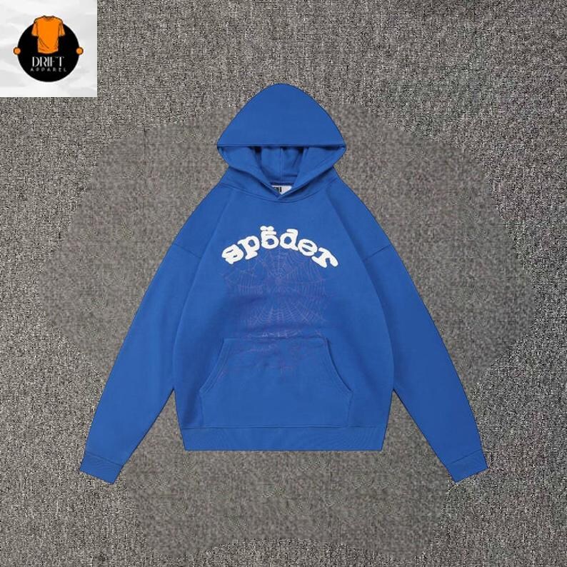 May include: A bright blue hooded sweatshirt featuring a large white arched text graphic that reads "sp&ouml;der" across the chest. Below the text is a faint, subtle spiderweb pattern. The garment includes a front kangaroo pocket and long sleeves.