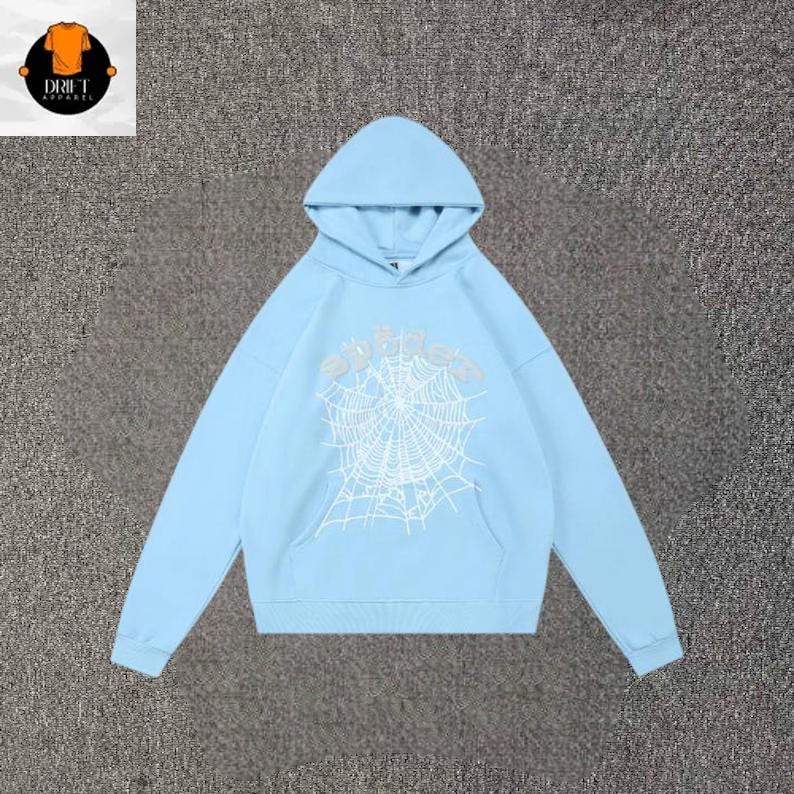 May include: A light blue hooded sweatshirt featuring a white spiderweb graphic printed on the center chest. The hoodie includes a front kangaroo pocket, long sleeves with ribbed cuffs, and a matching ribbed hem, providing a consistent color palette.