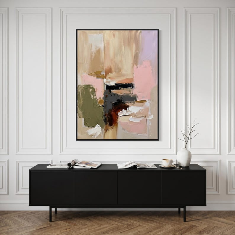 Puede incluir: Una pintura abstracta rectangular en un marco negro con pinceladas gruesas y superpuestas en tonos beige, rosa suave, verde oliva, gris oscuro y blanco, exhibida en una pared sobre un mueble de almacenamiento horizontal de color negro.