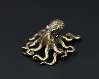 Könnte beinhalten: Eine detaillierte Messing-Oktopus-Figur mit acht gekräuselten Tentakeln. Die Skulptur hat eine strukturierte Oberfläche und ist vor einem dunklen Hintergrund platziert. Der Oktopus ist ein kleines Dekorationsobjekt.
