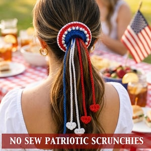 May include: A patriotic hair scrunchie with red, white, and blue accents. The scrunchie features a circular design with beaded trim and dangling strands. The strands are red, white, and blue, with heart-shaped accents. The text "NO SEW PATRIOTIC SCRUNCHIES" is at the bottom.