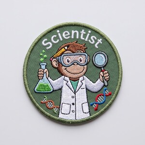 May include: A circular embroidered patch with an olive green background featuring a brown monkey wearing a white lab coat and safety goggles. The monkey holds a green liquid flask and a magnifying glass. Text reads Scientist with DNA strands.