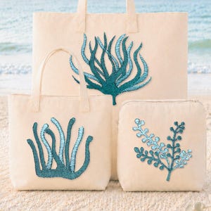 May include: A set of three cream-colored canvas bags featuring teal embroidered sea life designs. The largest bag is a tote, the medium bag is a smaller tote, and the third is a square pouch, all displaying distinct aquatic plant patterns.